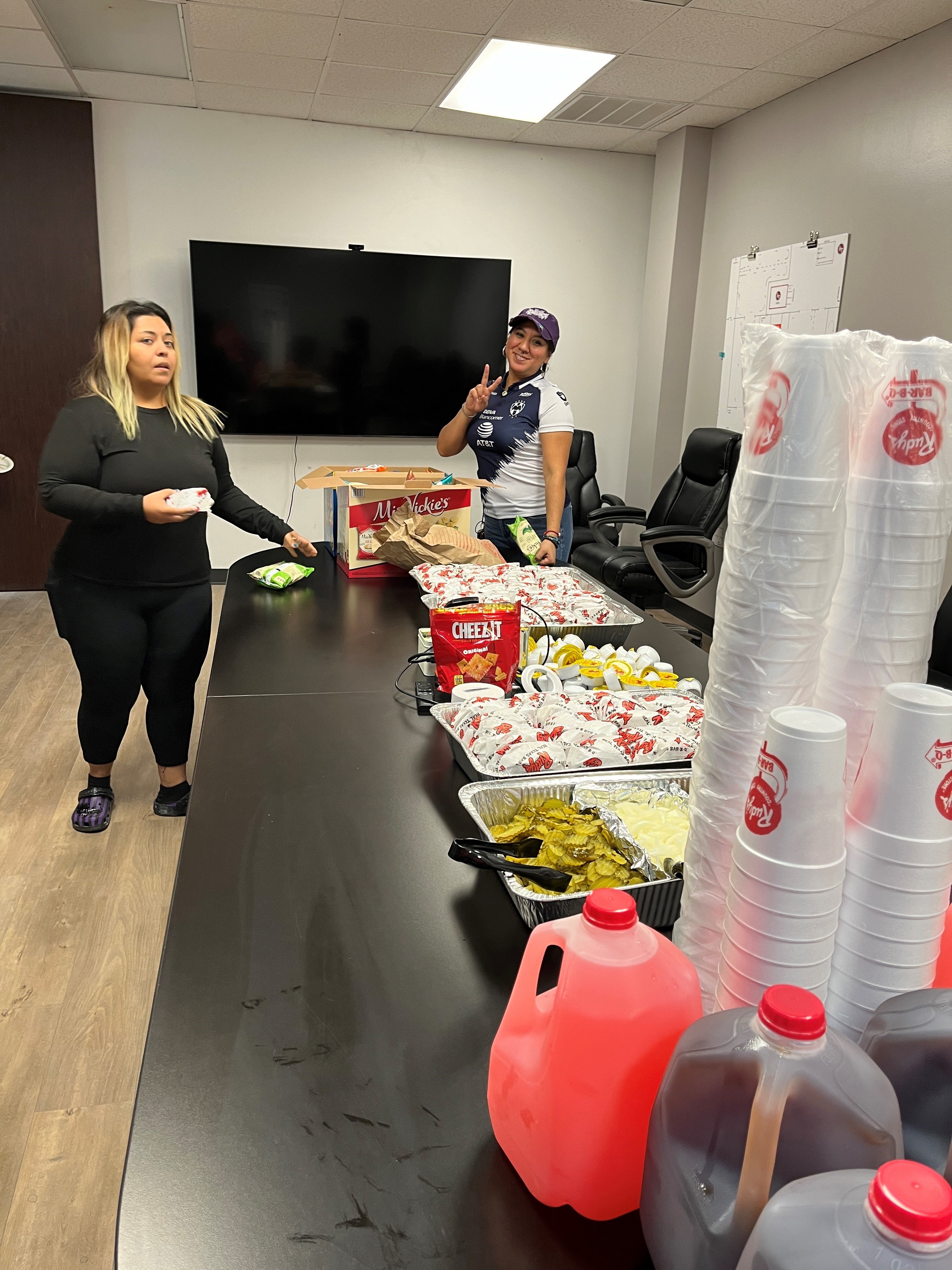 Two women setting up a table with food and drinks.