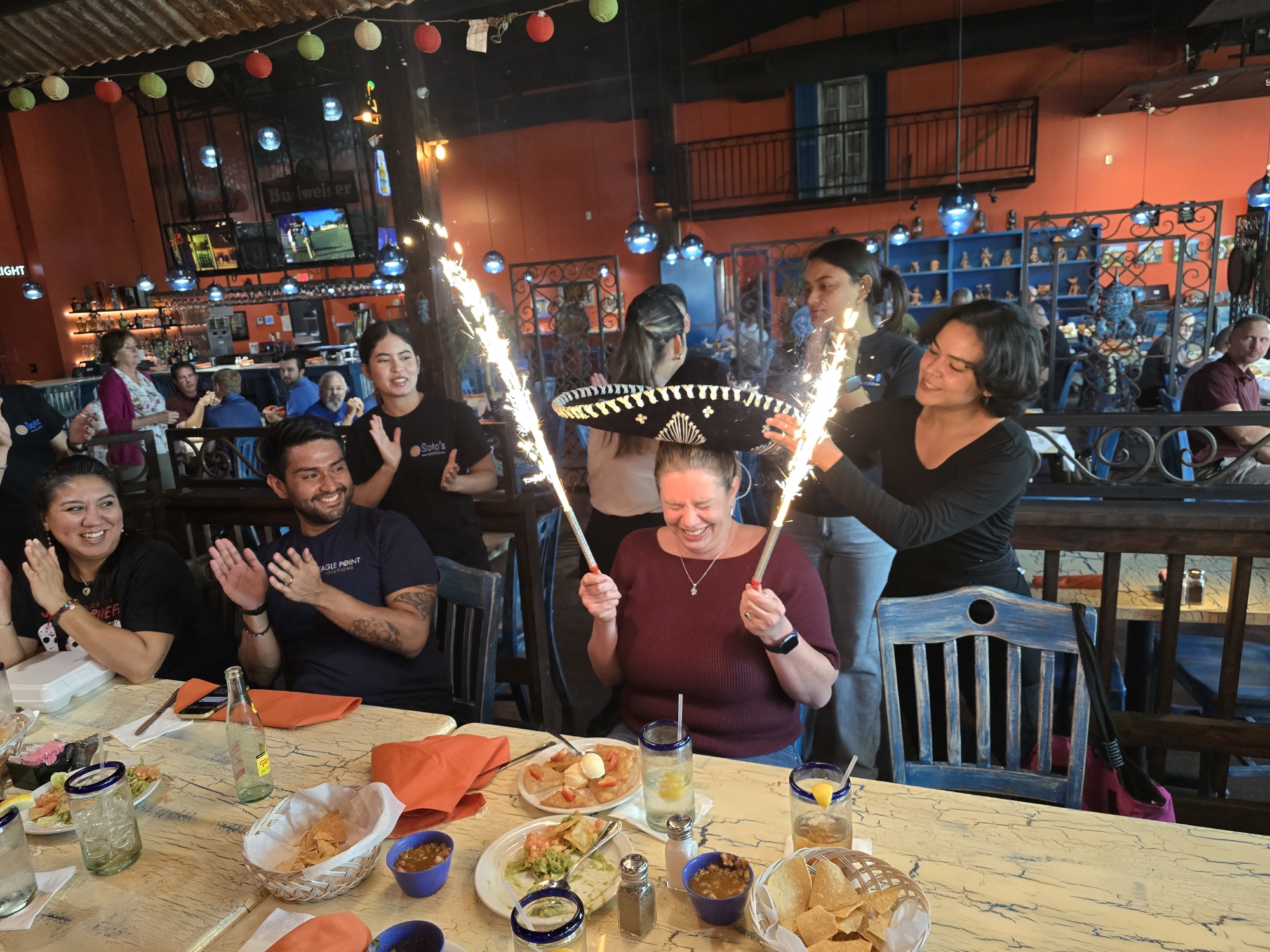 Woman with sombrero and sparklers celebrates at a restaurant.