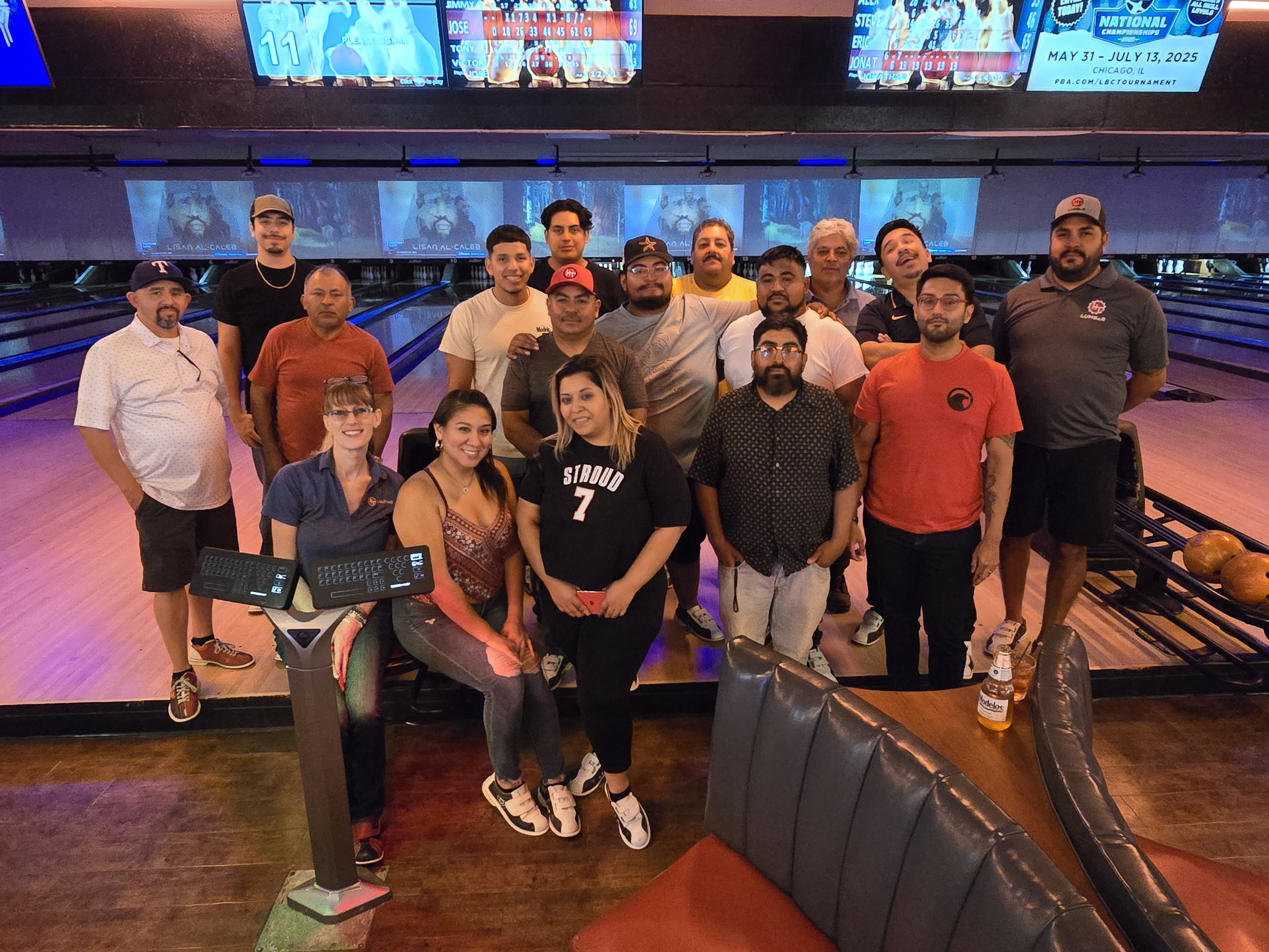 Group poses in bowling alley, smiling by the lanes.