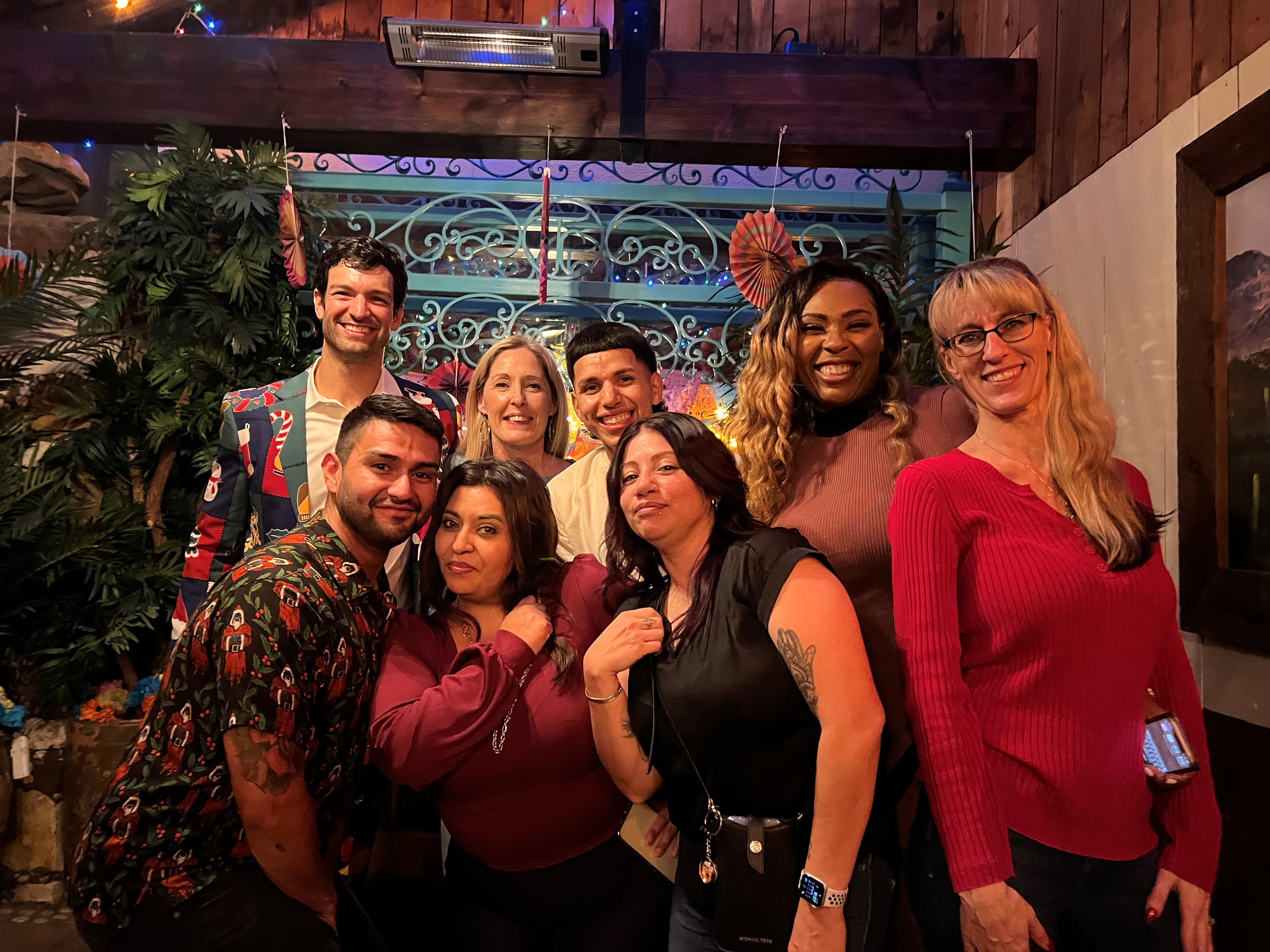 Friends pose indoors with festive background decor.